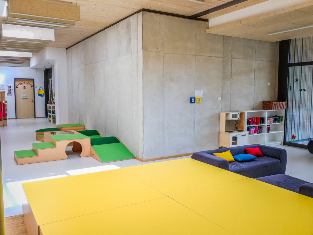 Hier ist der Gruppenraum mit Couch und Spielregalen zu sehen